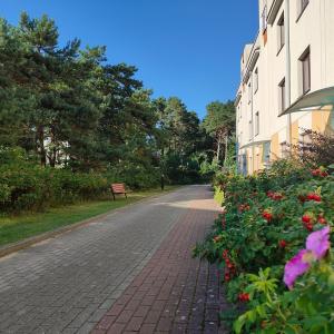 a brick road with flowers next to a building at Apartament Bursztynowy Jantar 2 pokojowy z ogrodzonym tarasem przy nadmorskim lesie in Jantar