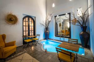un soggiorno con piscina con tavolo e sedie di Riad Come & Va Medina a Marrakech