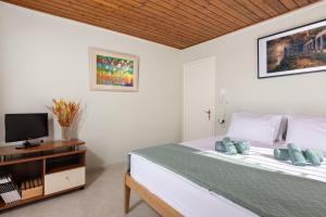 a white bedroom with a bed and a tv at Art Sounion, Seafront Elegance in Sounio