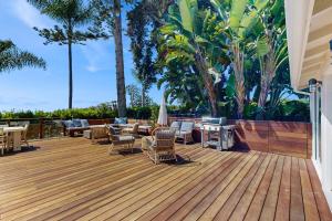una terraza con sillas, mesas y palmeras en Shoreline Bluffs Retreat, en Santa Bárbara