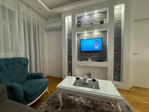 a living room with a couch and a tv on a wall at Apartman Mojsilović in Ub