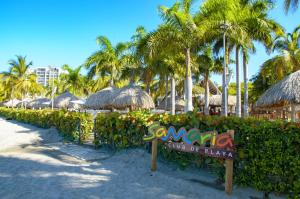un cartello su una spiaggia con palme e ombrelloni di Samaria Club de Playa - Pozos Colorados - By INMOBILIARIA VS a Santa Marta