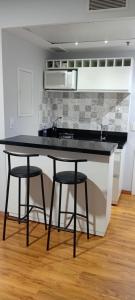 a kitchen with a black counter and two stools at Flat M1208 Ibirapuera in Sao Paulo