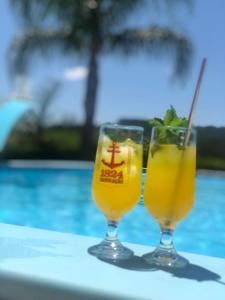 Dos vasos de jugo de naranja en una mesa junto a una piscina en Rancho SF Casa Texana, en Novo Hamburgo
