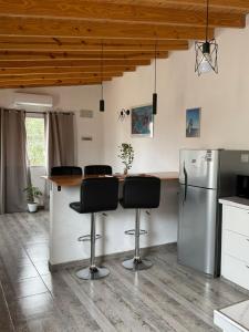 La cuisine est équipée d'un comptoir avec tabourets et d'un réfrigérateur. dans l'établissement Departamento Colonos Galeses, à Puerto Madryn