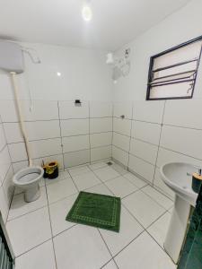 a bathroom with a toilet and a green mat on the floor at Suite com cozinha 250m do centro in São Thomé das Letras +9 photos