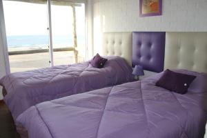 two beds in a bedroom with a large window at Arenas del Mar in Punta Del Diablo +160 photos