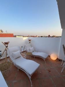 un grupo de sillas blancas sentadas en un techo en Dar Farah Riad luxe privé, 3ch, piscine chauffée, ptit déj, en Marrakech