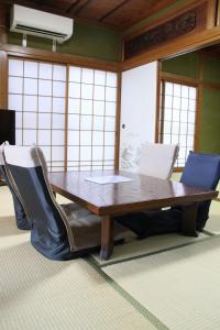 a wooden table with chairs and a laptop on it at Vacation rental PIGGY's Nichinan in Nichinan