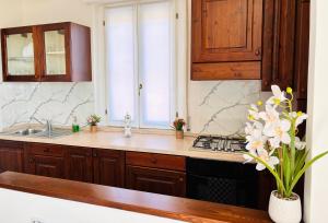a kitchen with wooden cabinets and a sink with flowers at Maison Du Soleil in Somma Lombardo