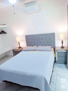 ein Schlafzimmer mit einem großen weißen Bett mit zwei Lampen in der Unterkunft Departamento El Tesoro - Olas Azules - 3 Min Malecón y Playas in Mazatlán