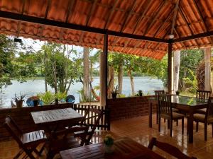a patio with tables and chairs and a view of the water at Chalé Marinas in Barreirinhas