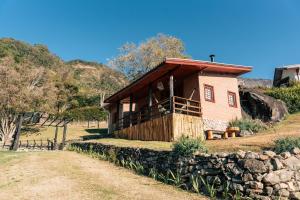 una pequeña casa en una colina con una pared de piedra en Casa Primavera, en São Bento do Sapucaí