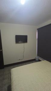 a bedroom with a bed and a tv on the wall at Be Happy Hotel in Guatemala