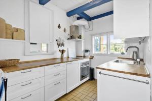 Una cocina con gabinetes blancos y un fregadero. en 5599-Gudhjem-Grevens-Dal-2, en Gudhjem