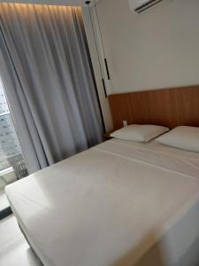 un letto bianco in una stanza con una finestra di Apt 01 quarto Resort Salinas Premium a Salinópolis