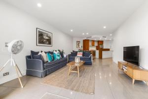 a living room with blue couches and a flat screen tv at Cotton Beach 97 Luxurious Mid Floor Apartment in Casuarina