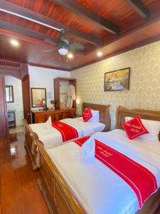 una camera da letto con due letti con lenzuola rosse e bianche di Villa Sirikili Namkhan River View a Luang Prabang