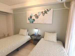 a bedroom with two beds and a painting on the wall at 浦和STAY in Saitama
