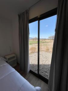 a bedroom with a bed and a large glass window at Eco Lodge - Campos de artaza in Belén