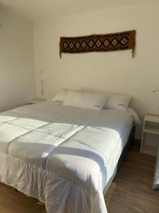 a bedroom with a large bed with white sheets at Eco Lodge - Campos de artaza in Belén