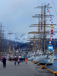 a group of ships docked in a harbor with people walking at Latidos del Sur in Ushuaia