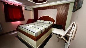 Un pequeño dormitorio con una cama y una silla. en Hotel By Hours Jurassic, en Barranquilla