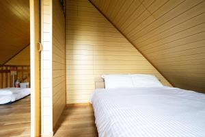 a bed in a room with a wooden wall at LAKE TOYA PREMIUM CABIN in Lake Toya