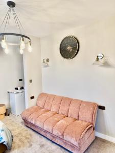 a couch in a living room with a clock on the wall at Double Deluxe Centre Apartment- Free Parking - Self Check-In - Cctv in Huddersfield
