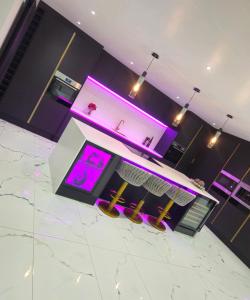 a kitchen with purple lighting and a counter with stools at Peaceful home in Moorside