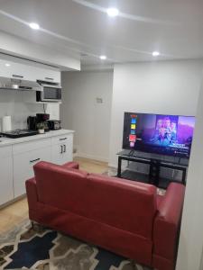 a living room with a red couch and a flat screen tv at Entire Basement Suite in Bonavista in Winnipeg