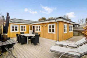 a yellow house with a table and chairs on a deck at FY377-Nyborg-Svalevej-6 in Nyborg