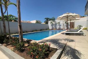 a swimming pool with an umbrella next to a building at Apartamento en Zona Playa Cerritos in Mazatlán