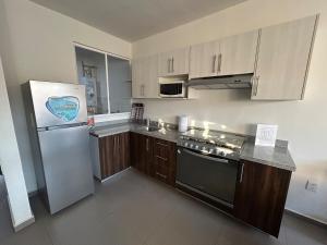 a kitchen with a stainless steel refrigerator and wooden cabinets at Apartamento en Zona Playa Cerritos in Mazatlán