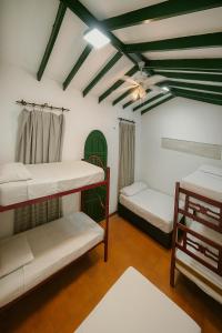 a room with three bunk beds and a ceiling at Hotel Galería Casa Paula Acosta in Rodadero