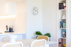 a dining room with a table and a clock on a wall at Surfrider - Beach front apartment with pool in Byron Bay