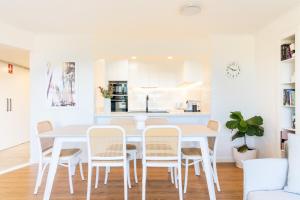 a white dining room with a white table and chairs at Surfrider - Beach front apartment with pool in Byron Bay