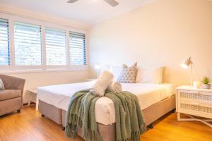 a bedroom with a bed and a chair and windows at Surfrider - Beach front apartment with pool in Byron Bay +19 photos