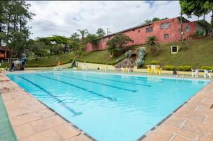 a large swimming pool with blue water and chairs at Chalé Recanto da Paz in Itu