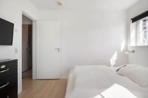 a white bedroom with a bed and a window at FY390-Bogense-Vestre-Engvej-118-st-tv in Bogense