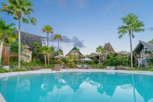 a large swimming pool with palm trees and houses at Cemara Hills Uluwatu, The Reserve - Cottages & Villas in Uluwatu