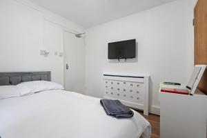 Harrow on the Hillにある6 Beds, 3 Baths, Harrow, Wembley, London 20mins Train to Wembley Stadium, London Maryleboneの白いベッドルーム(ベッド1台、薄型テレビ付)