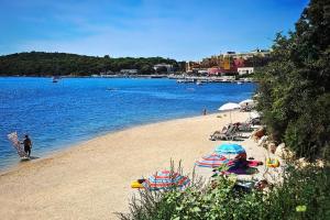 a beach with umbrellas and people on the water at Apartment Luzia in Banjole