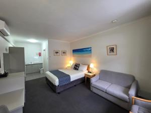 a hotel room with a bed and a couch at Hi 5 Glenelg Studio Apartment in Glenelg