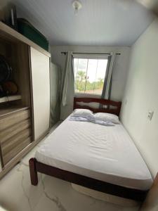 a small bedroom with a bed and a window at Casa com piscina próximo à praia in Palhoça +18 photos