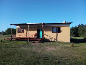 a small house with a blue door in a field at El Atardecer in General Lavalle