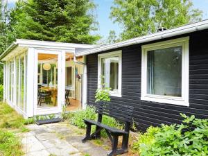 a black house with a bench in front of it at 6 person holiday home in Nykøbing Sj-By Traum in Nykøbing Sjælland
