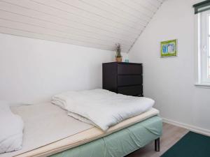 a bed in a room with a white wall at 5 person holiday home in Rømø-By Traum in Sønderby +37 photos