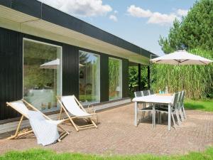 a patio with a table and chairs and an umbrella at 8 person holiday home in Asnæs in Asnæs