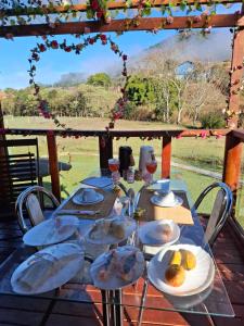 a table with plates of food on top at Chalés Refúgio no Campo in Santo Antônio do Pinhal